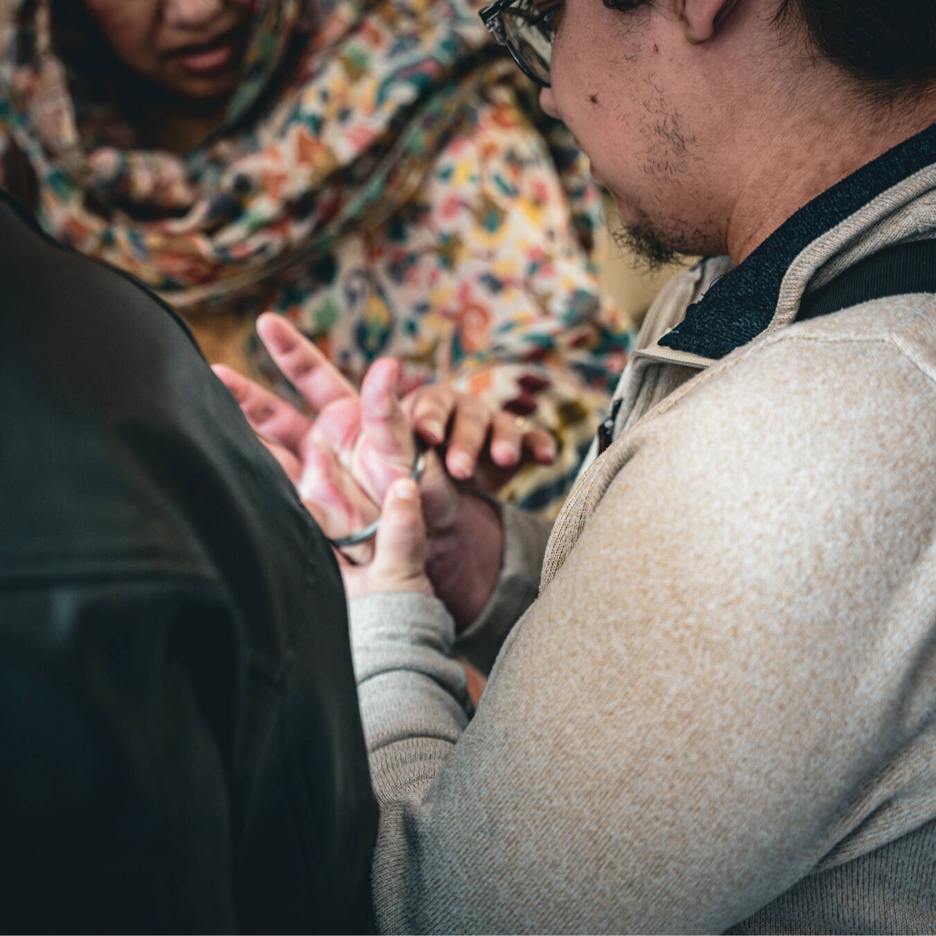 A close-up of a student trying on a silver bracelet or kara.